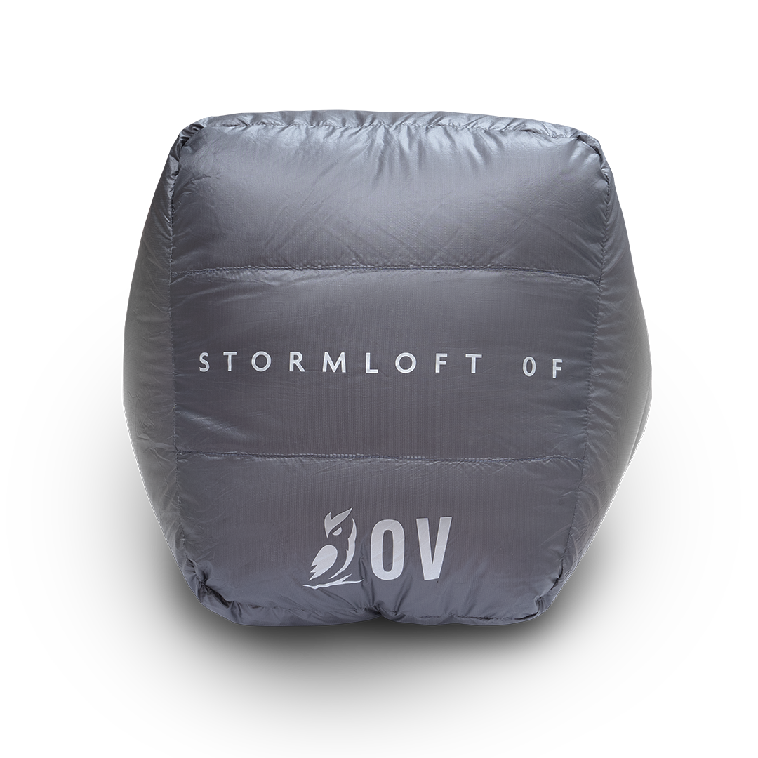 Bottom view of the Outdoor Vitals StormLoft 0F topquilt packed inside its compression stuff sack, displaying the printed product name and OV owl logo.