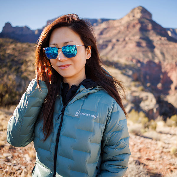 A woman in a NovaPro down jacket in front of a desert canyon.