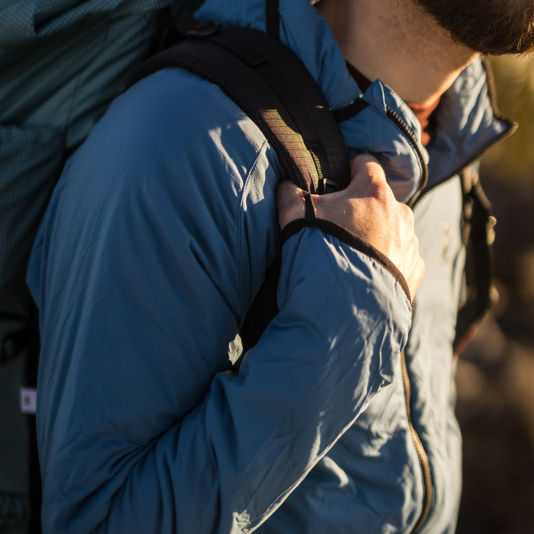 Close-up of the Outdoor Vitals Vario Jacket showing the thumb loops while holding a backpack
