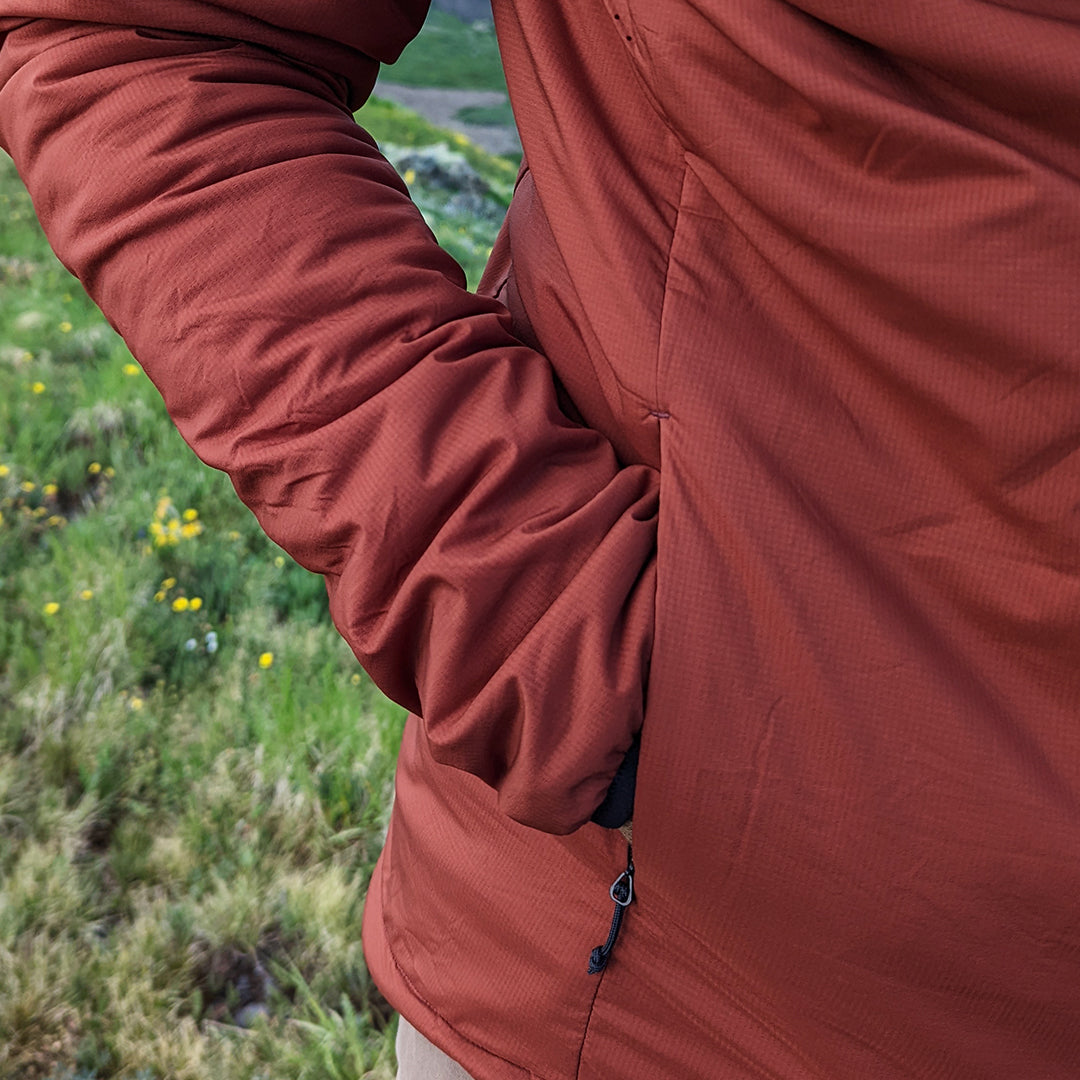 Close-up of a jacket showing a hand in the zippered side pocket