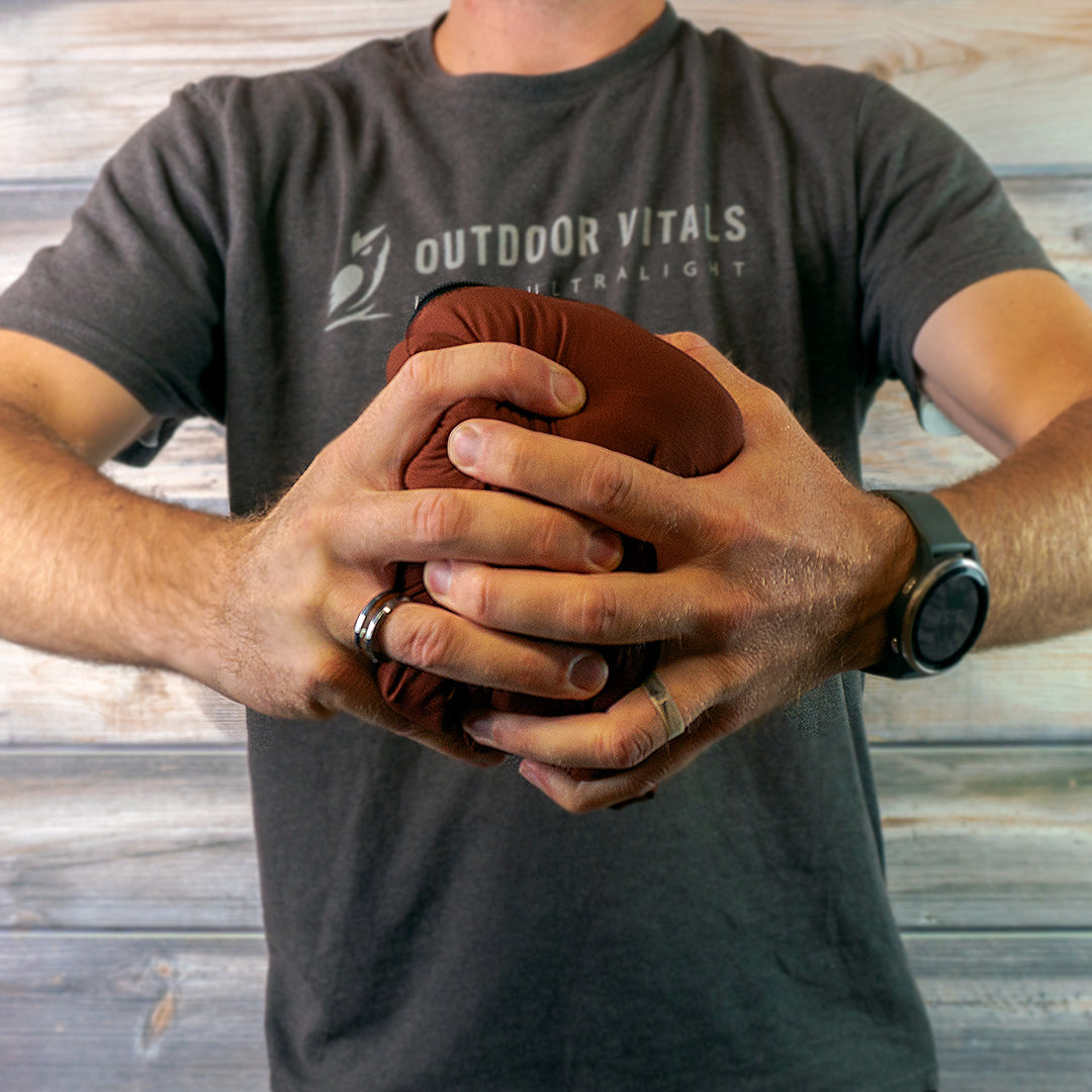 Man compressing a jacket into a tight ball to show packability.