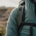 Close-up view of the padded shoulder strap on the Outdoor Vitals KotaUL Ultralight Travel & Adventure Backpack, showcasing the printed bird logo, ripstop fabric, breathable mesh padding, and adjustable sternum strap buckle.