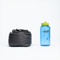 Compressed gray backpacking quilt in its stuff sack shown next to a Nalgene water bottle for size comparison.
