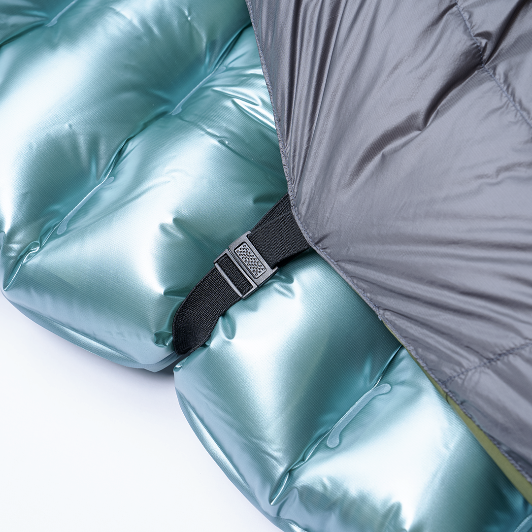 Close-up of the pad attachment strap and buckle securing the Outdoor Vitals StormLoft Down TopQuilt to an inflatable sleeping pad.