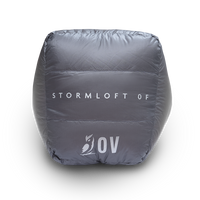 Bottom view of the Outdoor Vitals StormLoft 0F topquilt packed inside its compression stuff sack, displaying the printed product name and OV owl logo.