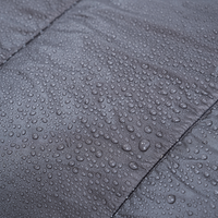 Close-up of water droplets beading on the surface of a quilt fabric, showing its water-resistant properties.