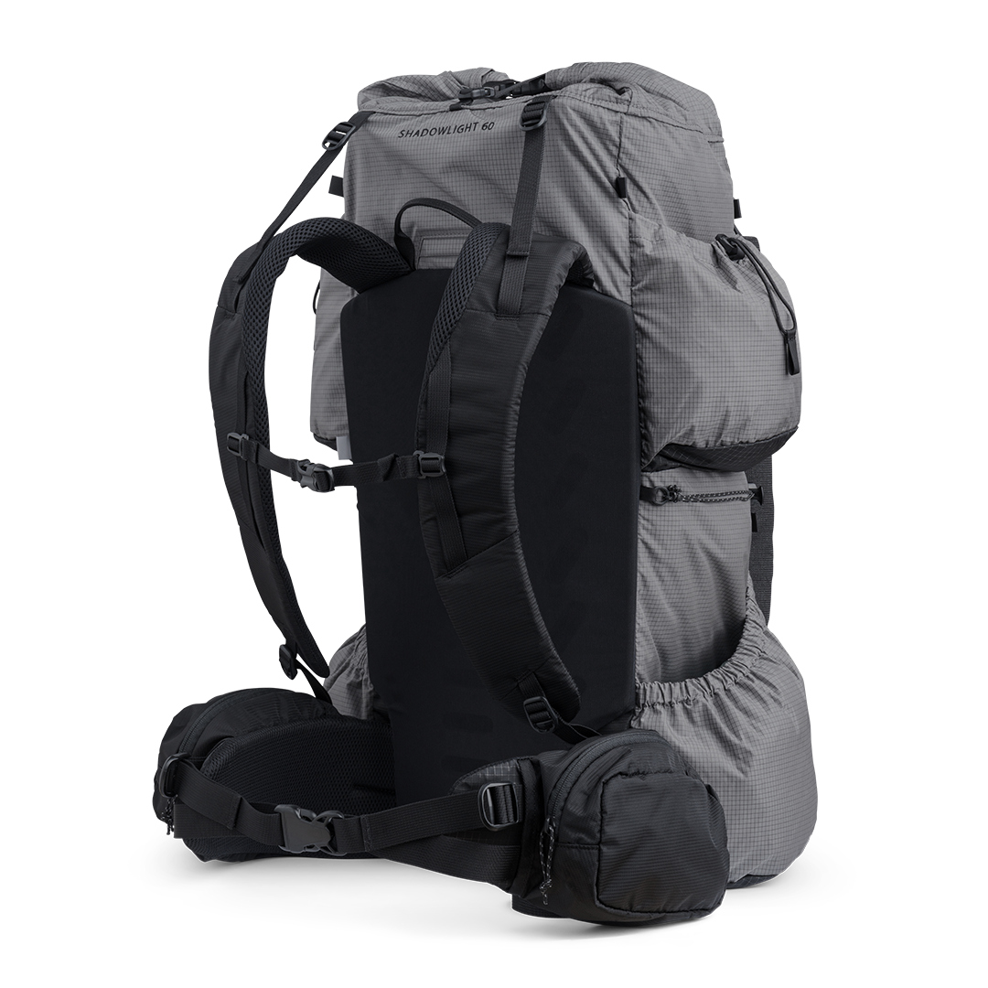Side and rear angled view of the Shadowlight 60 ultralight backpack in gray, showing shoulder straps, hip belt, and large storage pockets.