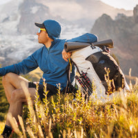 Hiker wearing an Active Hoodie resting on a mountain with a CS40 Ultra backpack.