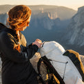Woman in a hooded jacket adjusting her CS40 Ultra backpack on a rocky summit