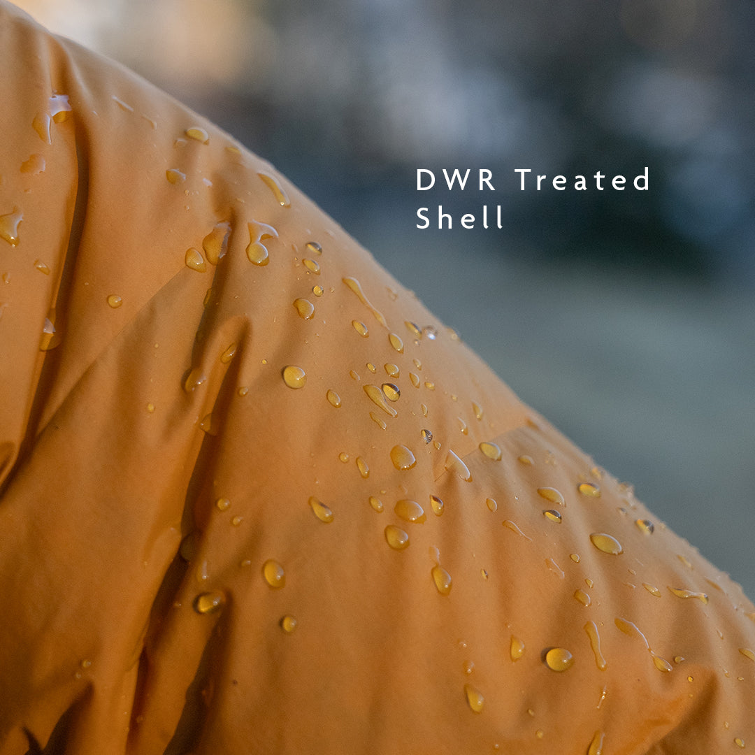 Close-up of jacket shell fabric with water beading on the surface, demonstrating durable water-resistant (DWR) treatment.