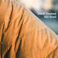Close-up of a warm tan or camel-colored fabric surface with water droplets beaded on it and the text 'DWR Treated 15D Shell' in the upper right.