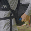 Hiker reaching into the bottom pocket of the Outdoor Vitals Skyline 30 Fastpack while wearing it.