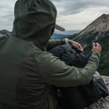 rear view of man wearing fleece hoodie on top of rugged mountain peak