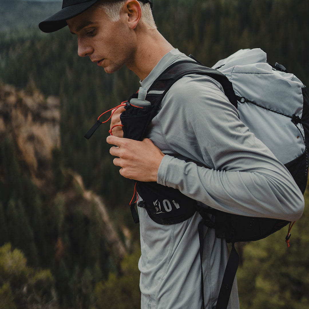 Close-up side profile of a hiker wearing the Outdoor Vitals Skyline 30 Fastpack, highlighting the running-vest style harness with front shoulder strap pockets and hydration flask storage.