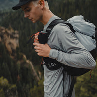 Close-up side profile of a hiker wearing the Outdoor Vitals Skyline 30 Fastpack, highlighting the running-vest style harness with front shoulder strap pockets and hydration flask storage.