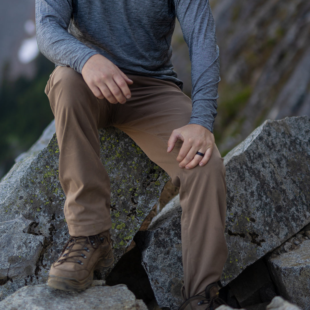 Hiker resting on rocks wearing Outdoor Vitals Satu Adventure Pants.