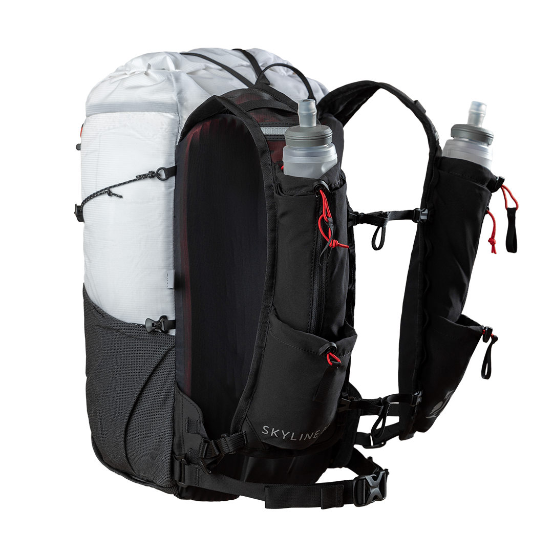 Studio product shot of the Outdoor Vitals Skyline 30 Fastpack featuring its running vest-style shoulder harness, dual adjustable sternum straps, lower webbing hip belt, and integrated harness pockets holding two soft water flasks.