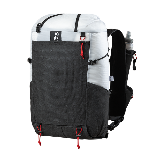Front side view of the Outdoor Vitals Skyline 30 Fastpack highlighting the expandable front stretch-mesh pocket, side mesh pocket, top roll-closure straps, and running vest harness equipped with a water flask pocket.