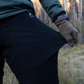 Close-up of a person pulling outwards on the thigh fabric of Outdoor Vitals Highline Thermal Leggings, demonstrating the material's stretch and elasticity.