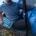 Camper sitting in a tent wearing an Outdoor Vitals Altitude sun hoodie and thermal leggings.