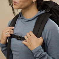 Close-up of a woman wearing Outdoor Vitals merino hoodie holding backpack straps