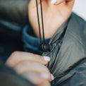 Close-up of a person tightening the drawstring and cord lock on a insulated sleeping bag, adjusting the fit for warmth.