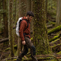 Backpacker hiking through a wooded trail wearing the Outdoor Vitals Vario Jacket