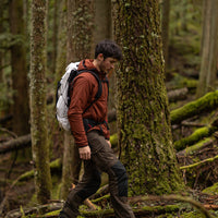 Backpacker hiking through a wooded trail wearing the Outdoor Vitals Vario Jacket