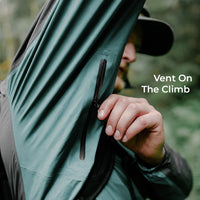 A close-up of a person wearing a lightweight rain jacket, unzipping the underarm vent. The text 'Vent On The Climb' is displayed on the right side.