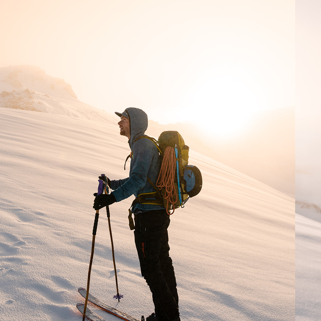 Backcountry skier wearing the Outdoor Vitals Vario Jacket touring on a snowy mountain