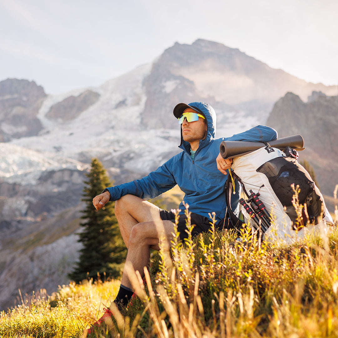 Hiker wearing a Ventus Active Hoodie resting on a mountain with a backpack.