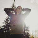Low-angle view of a woman adjusting her hair while wearing an Ventus Active Hoodie.