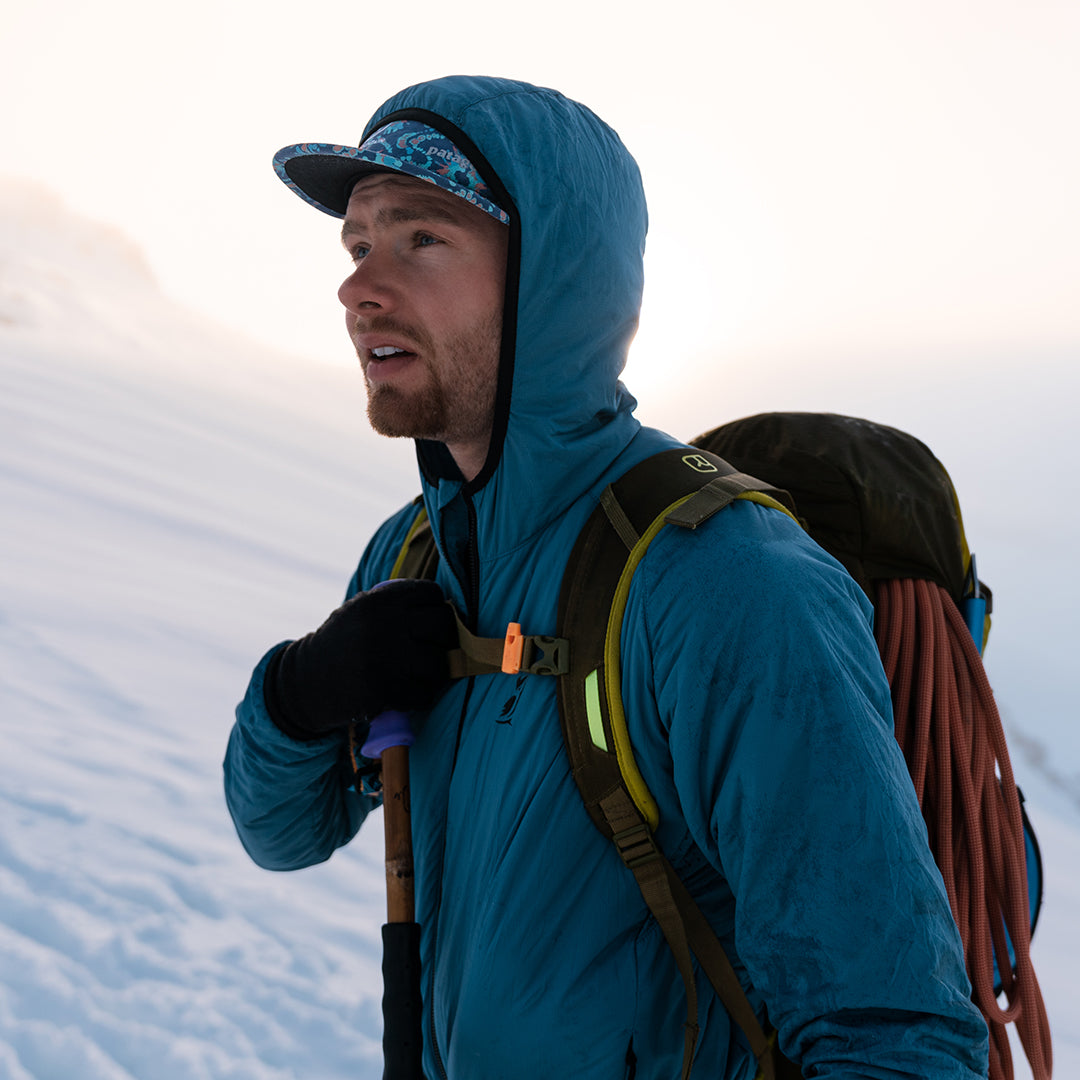 Hiker wearing the Outdoor Vitals Vario Jacket on a snow-covered mountain summit