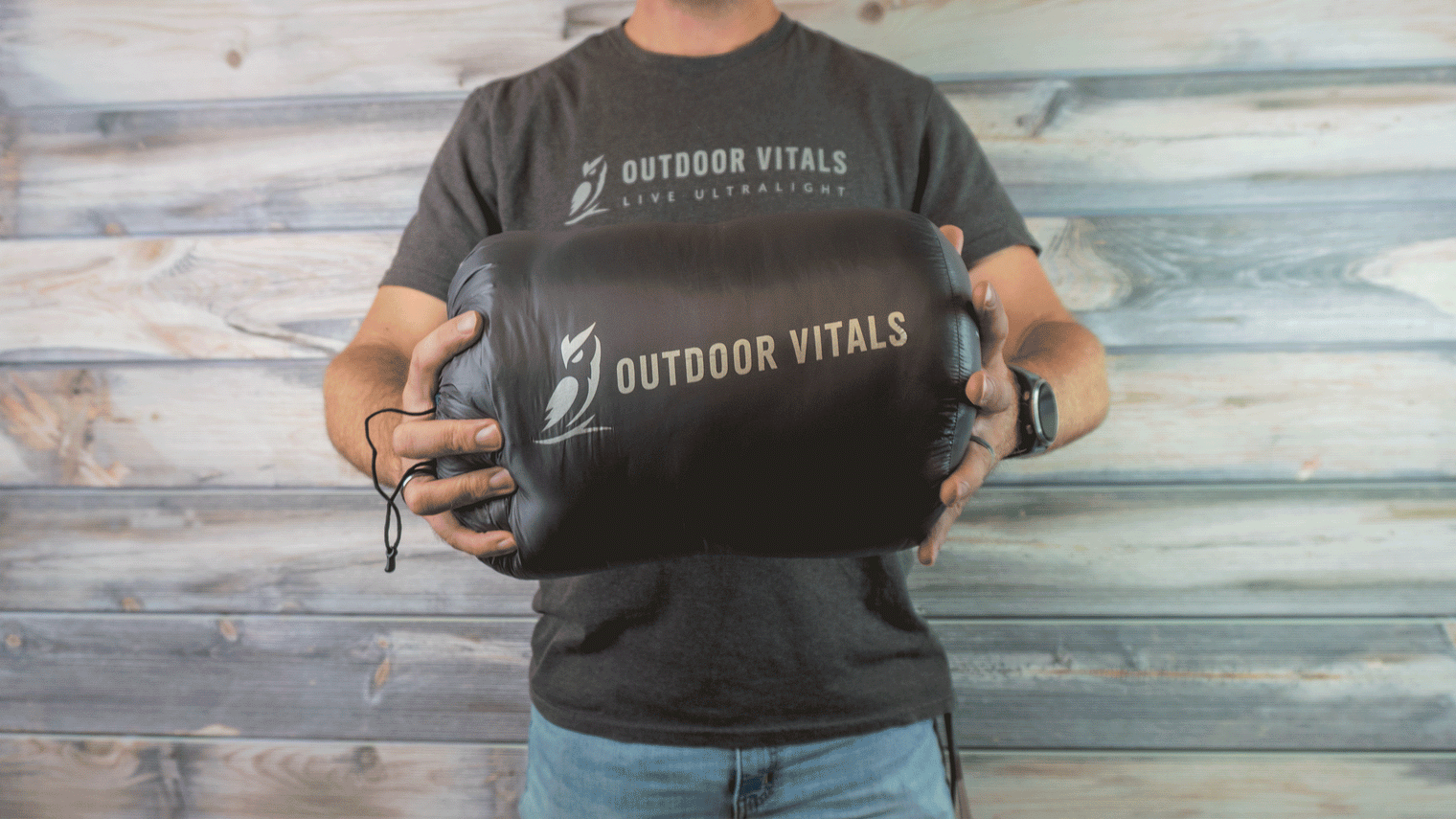 A person holding a packed and compressed Outdoor Vitals StormLoft Down UnderQuilt in its stuff sack to demonstrate its compact size.