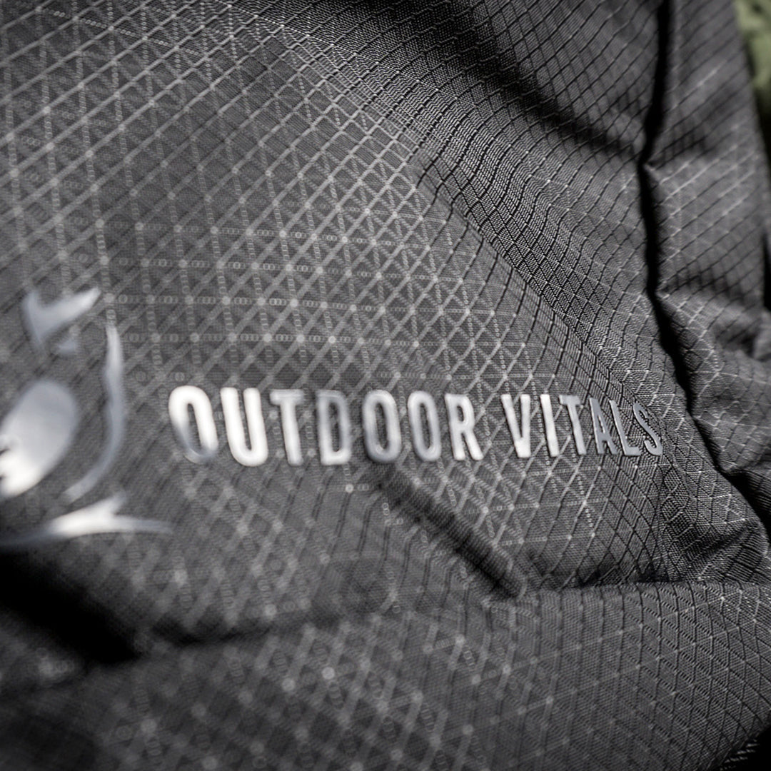 Extreme close-up of the Outdoor Vitals logo and brand name printed on the durable grid-patterned ripstop fabric of the KotaUL Ultralight Travel & Adventure Backpack.