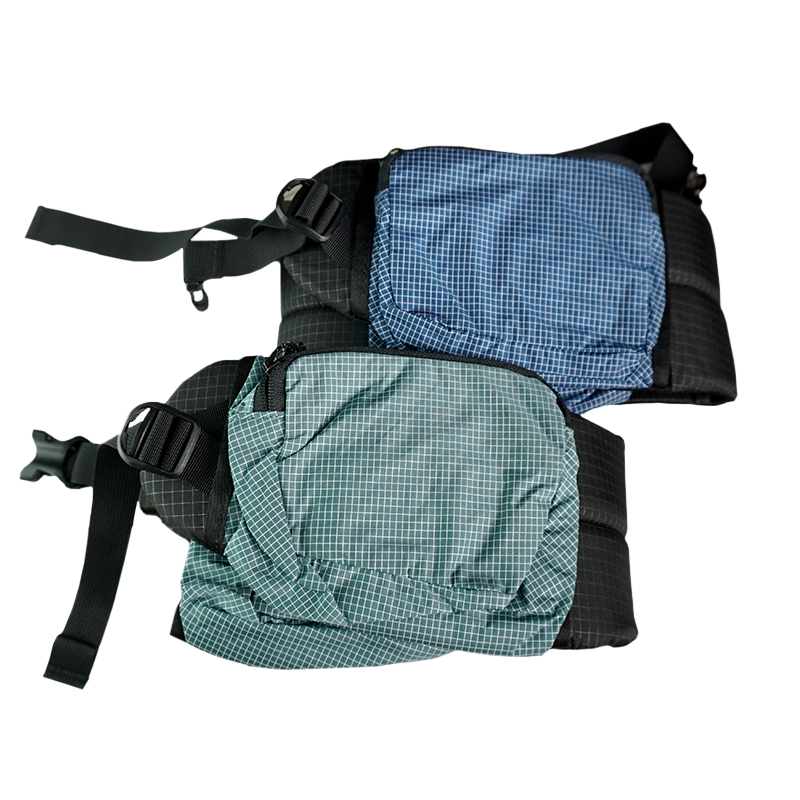 Product shot showing the detachable hip belt pockets of the Outdoor Vitals Shadowlight Carbon 60 Backpack, featuring durable ripstop grid fabric and zippered closures.
