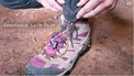 Close-up of the bottom hem of Outdoor Vitals Satu Adventure Pants, highlighting the removable lace clip feature secured to a hiking boot's laces.