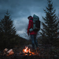Camper standing by a fire with the Shadowlight Ultralight Backpack