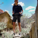 Full-length shot of a woman hiking through a desert canyon wearing Outdoor Vitals Satu Adventure Shorts and a backpack.
