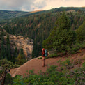 Backpacker wearing the Women's Outdoor Vitals Vario Jacket overlooking a mountain valley