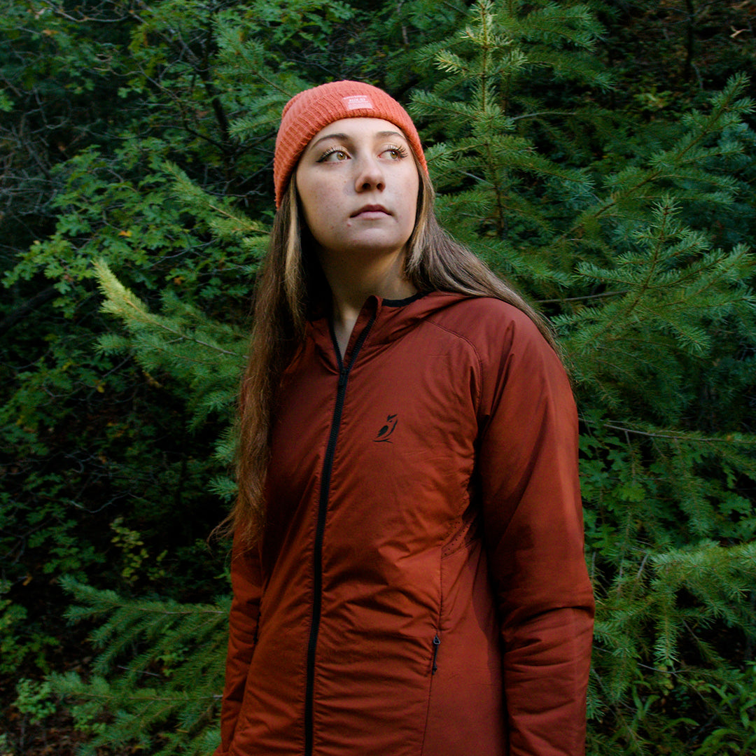 Woman wearing the Women's Outdoor Vitals Vario Jacket among evergreen trees